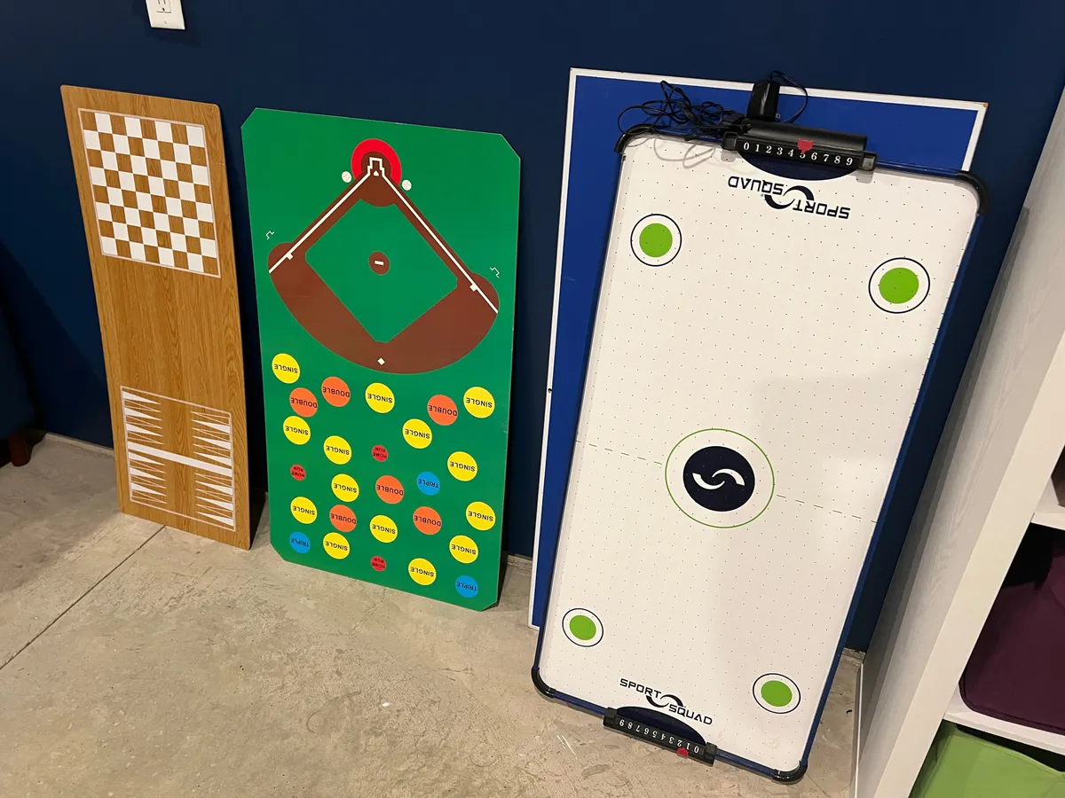 A vibrant interior view of a game room featuring a chessboard, baseball-themed game board, and an air hockey table. The space is inviting and clearly set up for family game nights and interactive fun.