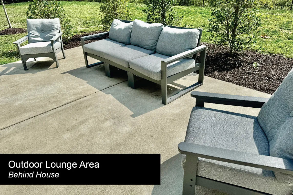 An inviting exterior scene featuring a green lawn bordered by bushes, with an outdoor lounge sofa and two armchairs. The space is ideal for socializing, relaxing, or letting pets play, reinforcing the sense of community and leisure activities mentioned in the section.